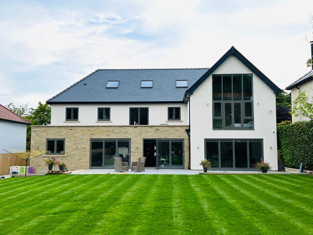 Completed house renovation with stone and render exterior and striped lawn